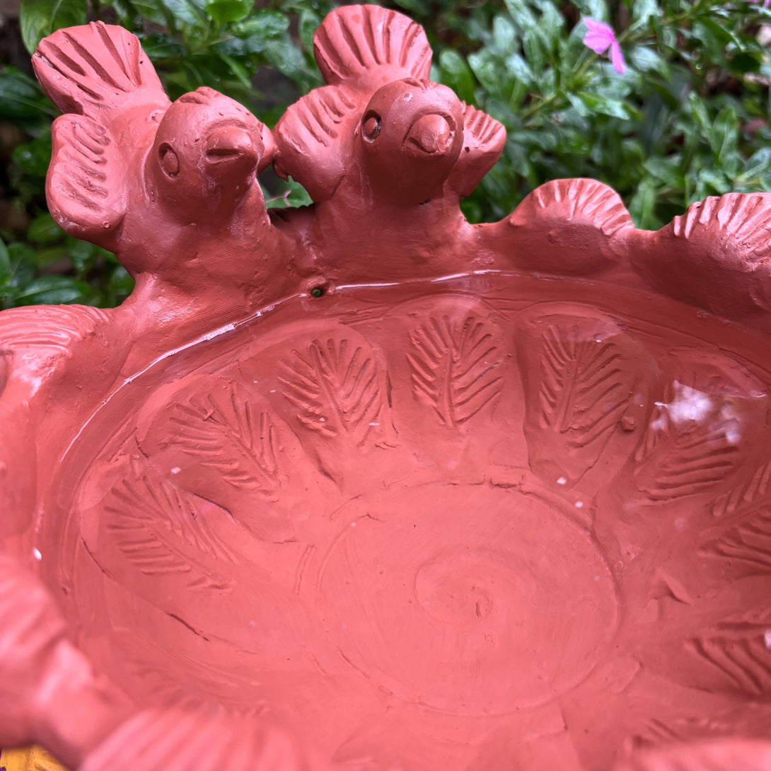 Red terracotta bowl with chicken design on a garden background